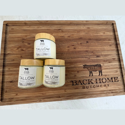 Three Grass Fed Beef Tallow Lotions on a wooden cutting board branded 'Back Home Butchery'.